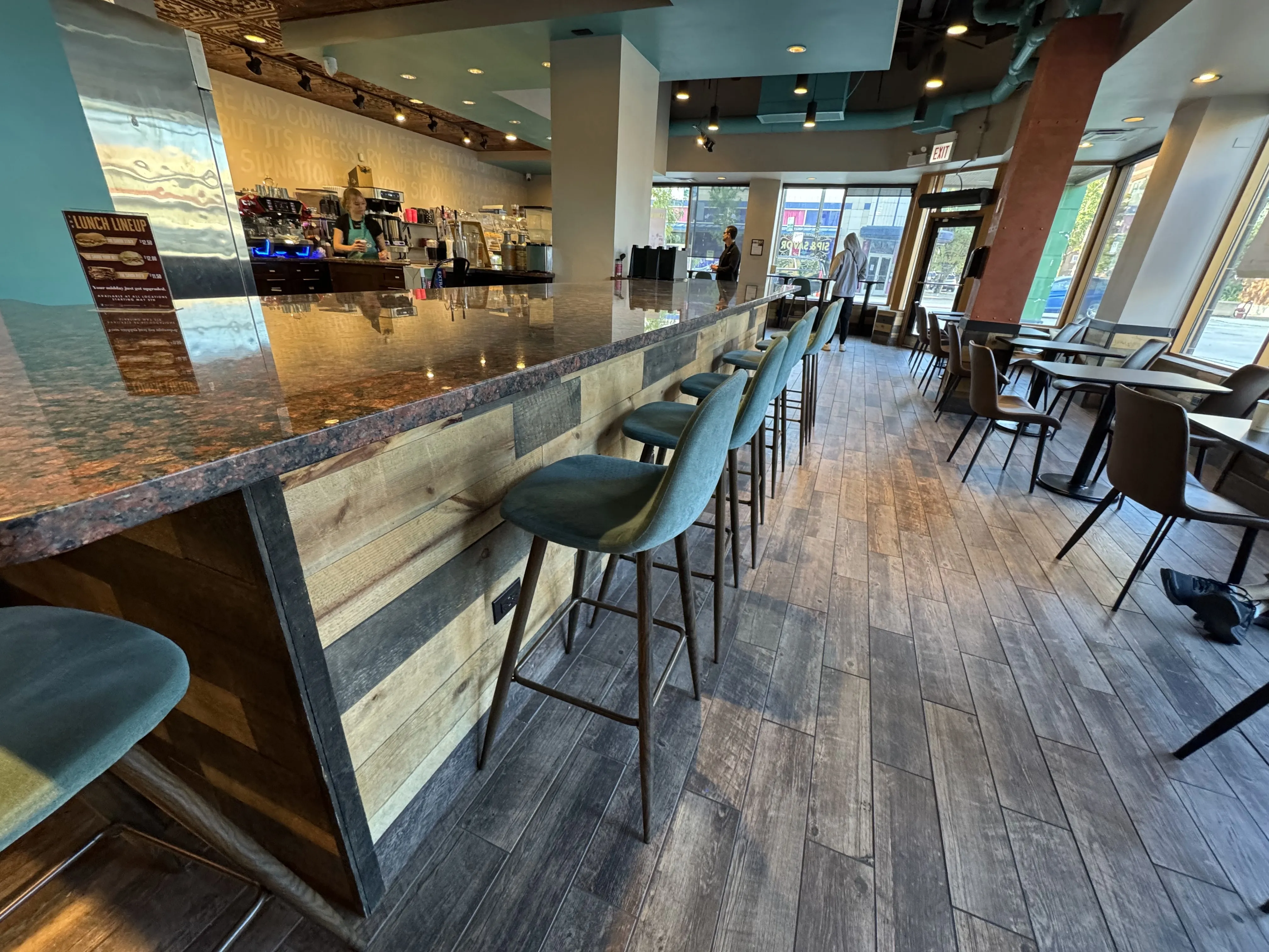 Photo from the back of Sip & Savor looking outwards. There's bar seating to the left, and many small 2-person cafe tables to the right and elsewhere