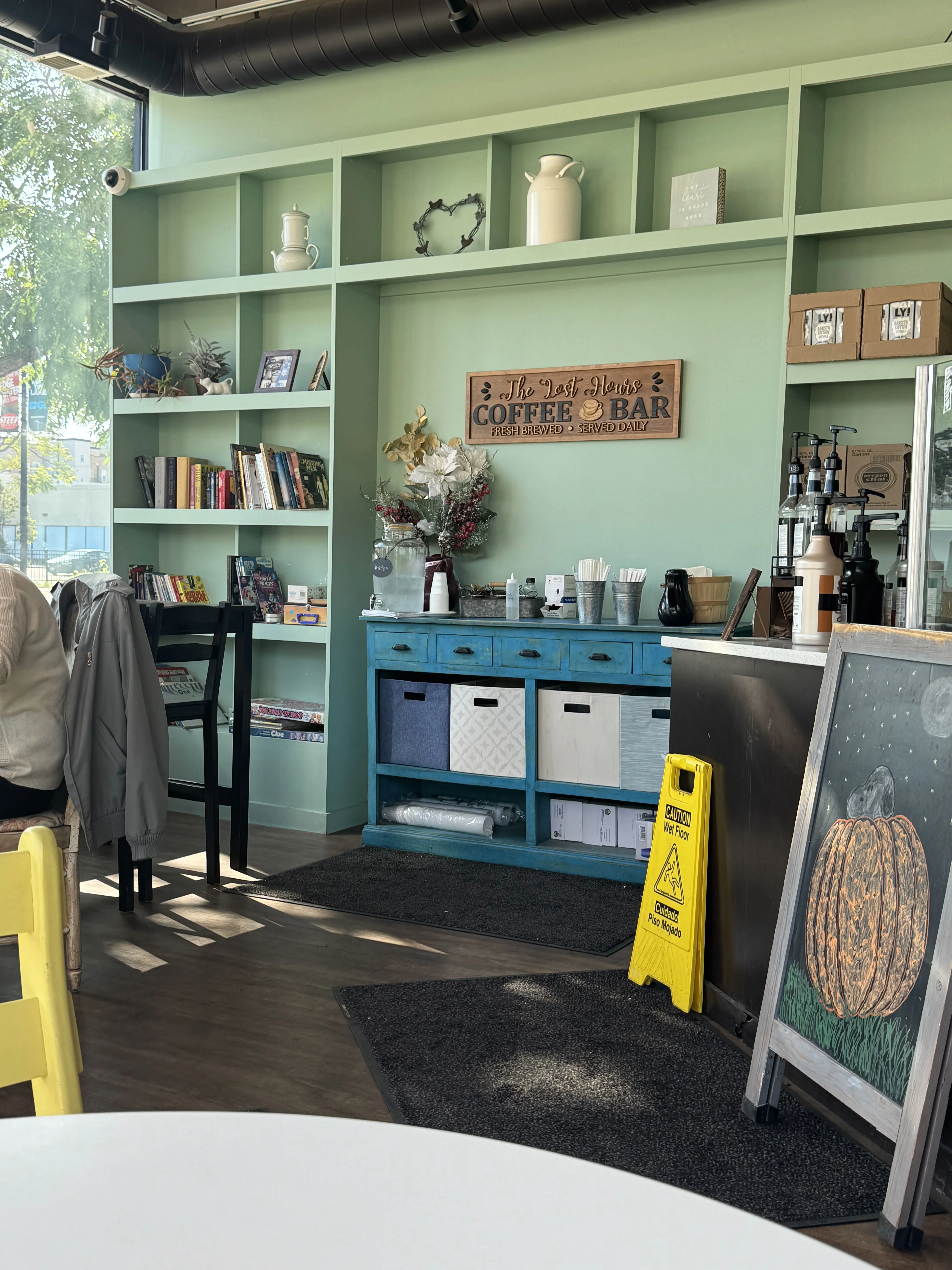 Side area of the cafe, with a complex shelf with books and coffee supplies