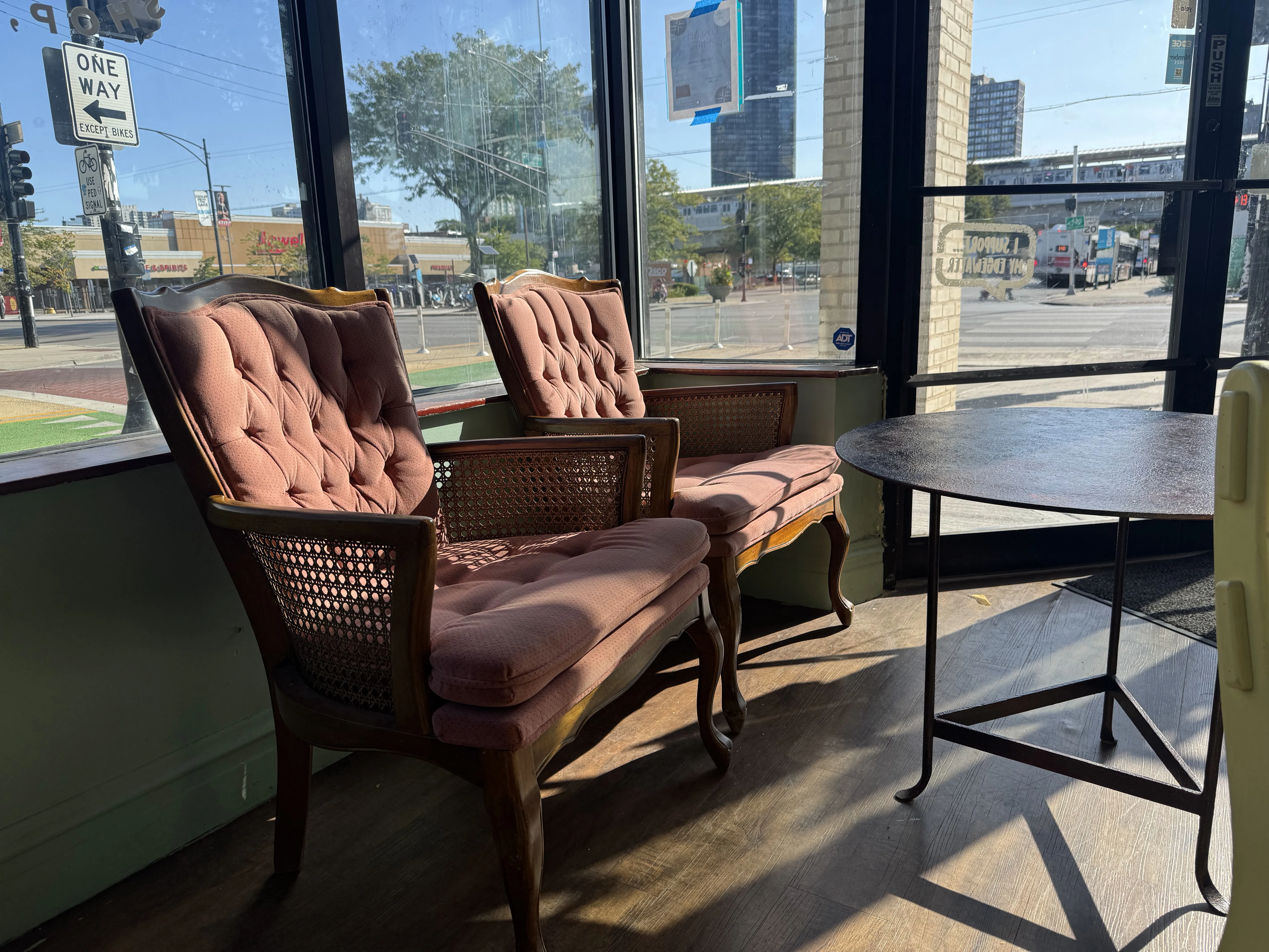 Two brownish armchairs in the sunlit front of the cafe