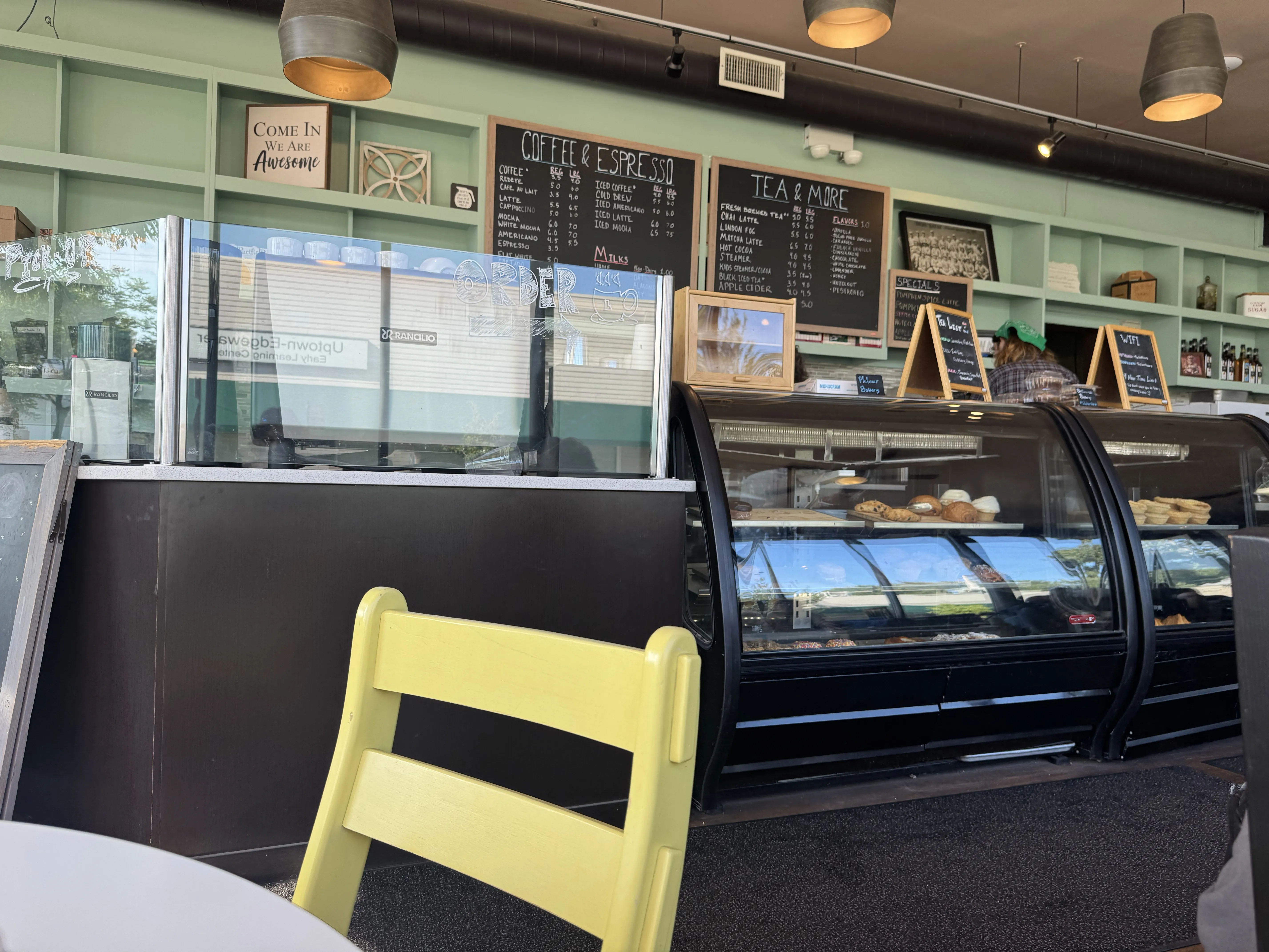 Front view of the cafe. Pastry shelves are visible with chalk boards and shelves in the back.