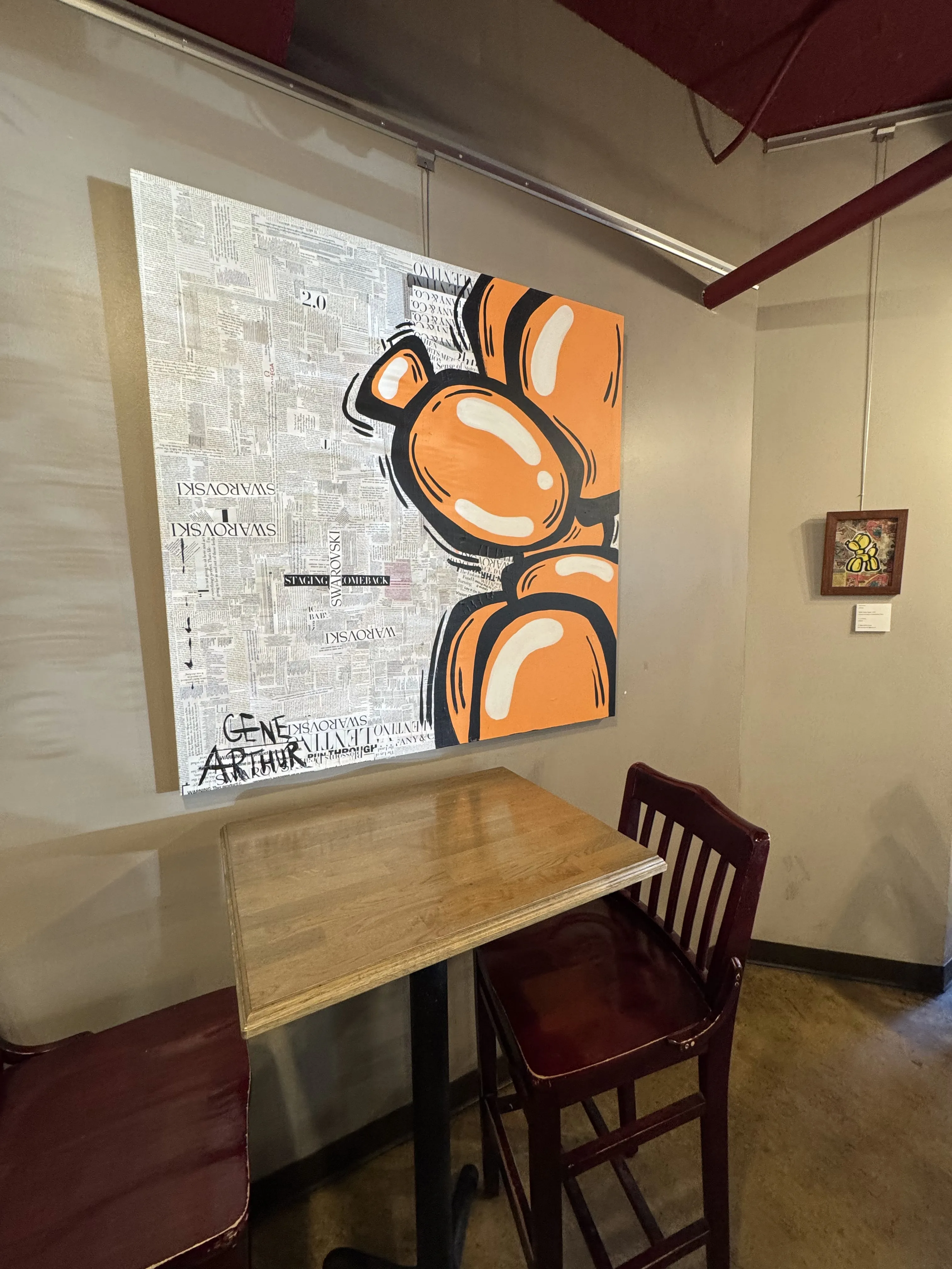 1 large canvas depicting an orange balloon animal above a 2-person cafe table