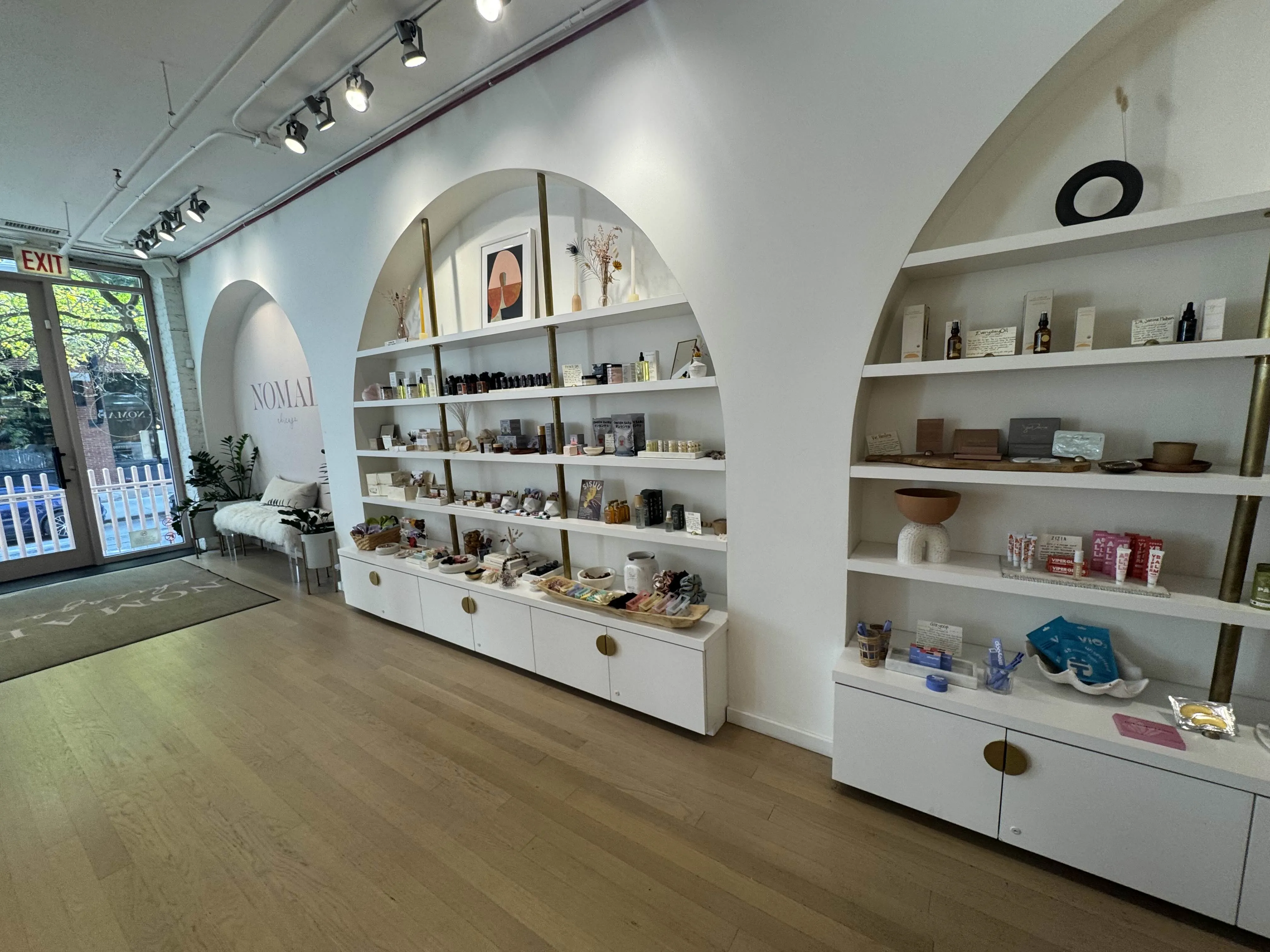 Front of store, featuring large open space with two curved insets in the wall with shelves packed with beauty/grooming supplies. Very small-brand stuff.