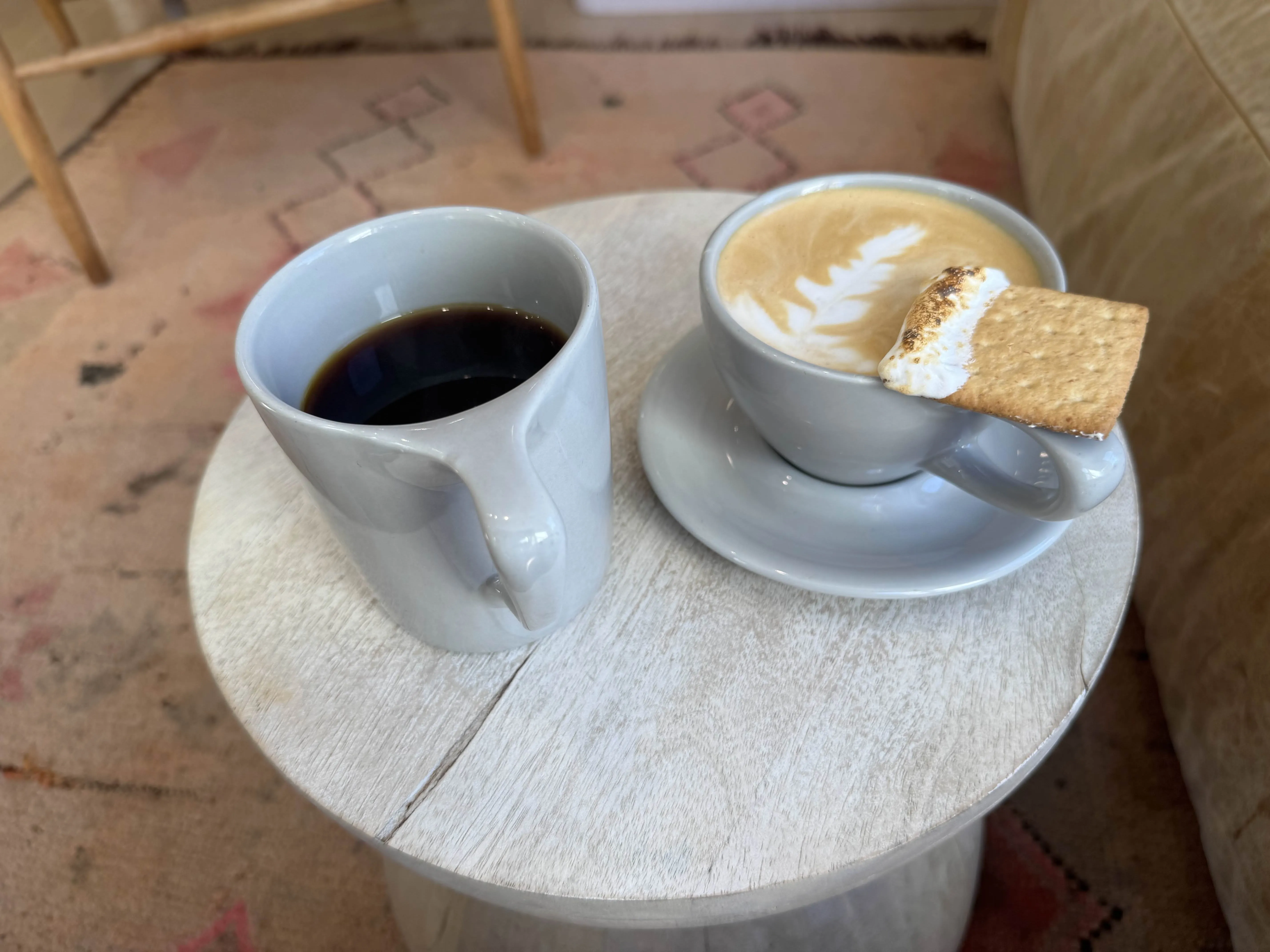 Big ol mug with pour-over coffee in it beside a pretty latte with a graham cracker and marshmallow