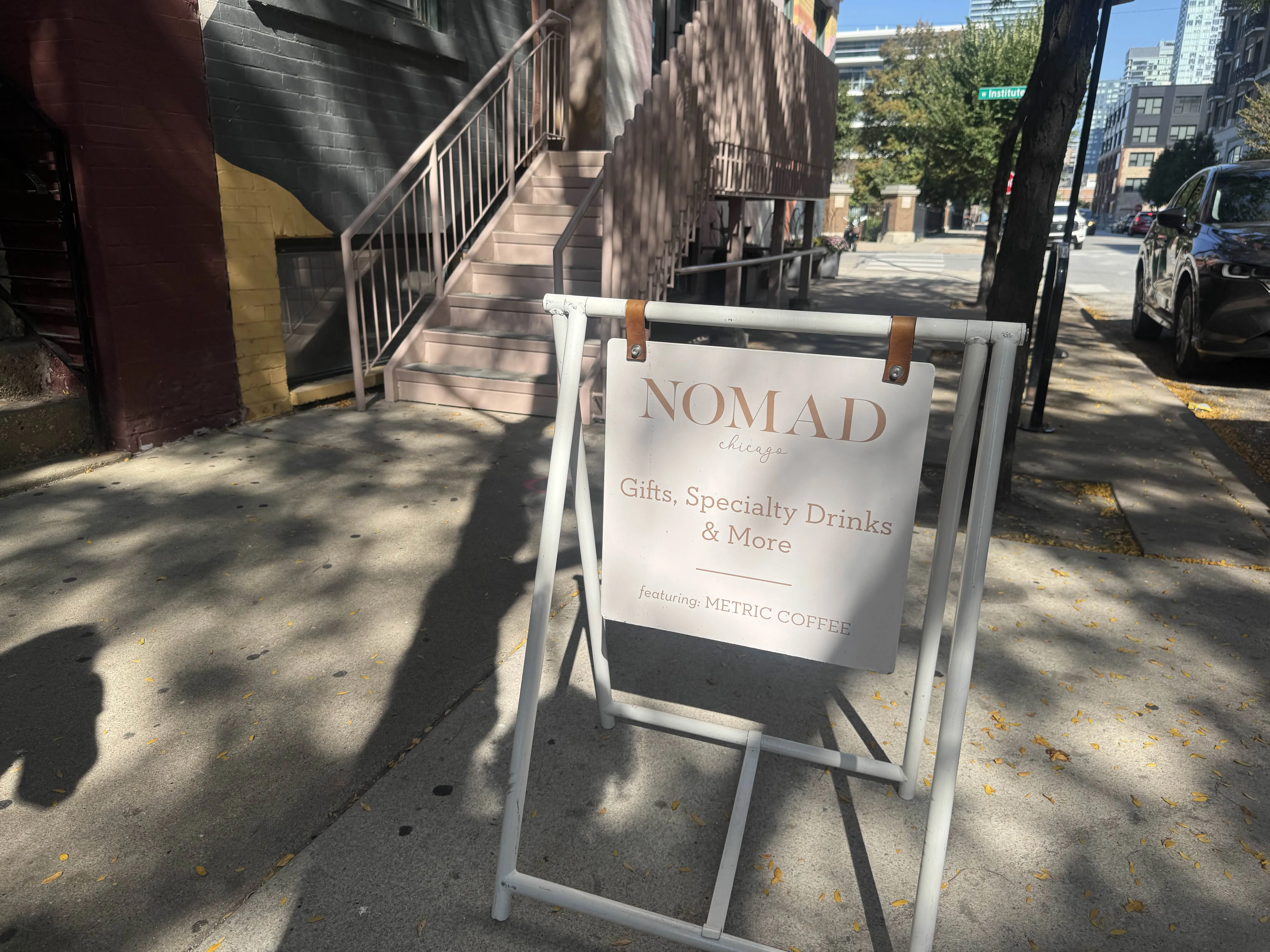 Sandwich board for the shop, reading NOMAD Chicago. Gifts, Specialty Drinks & More. Featuring: METRIC COFFEE