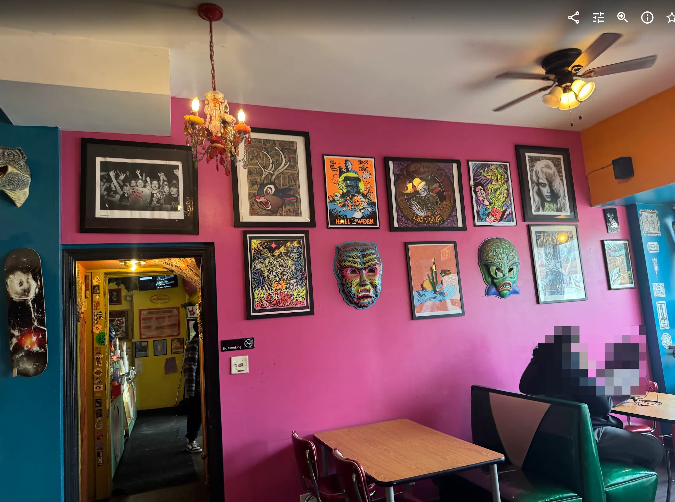 A pink and blue wall in the cafe space. More art on the walls, wooden tables in the foreground with vintage booth seating