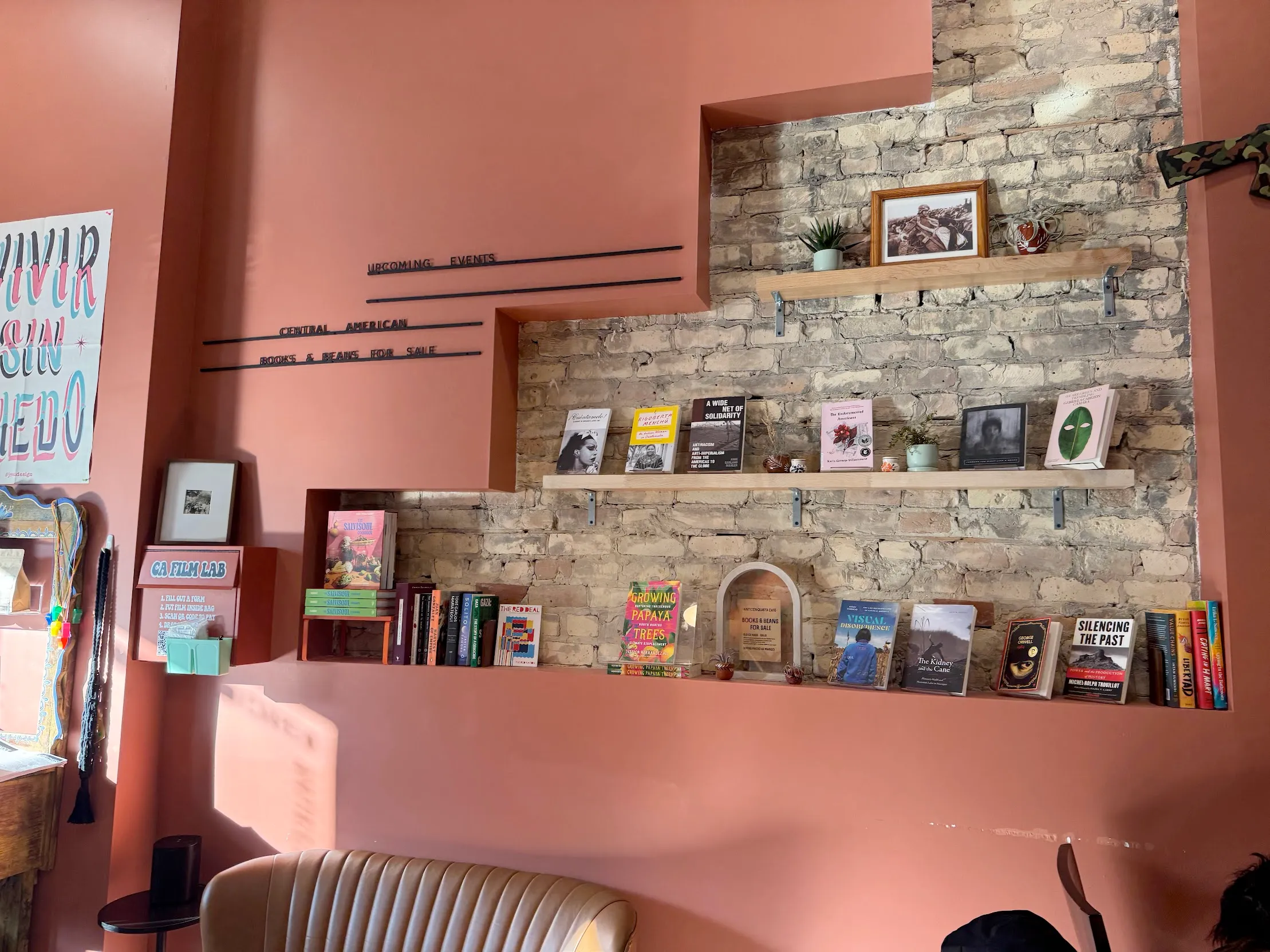 Exposed bricks with shelves hosting anticolonial literature for sale in Anticonquista cafe
