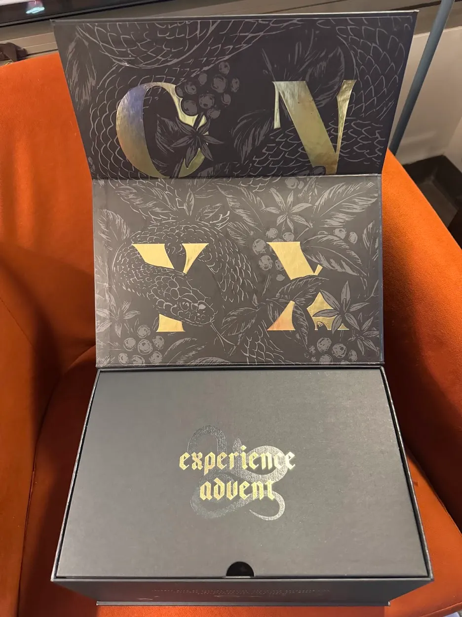 Black onyx box opened revealing a black Snake design wrapped around golden lettering reading ONYX. On the bottom flap is another snake around the words 'experience advent'